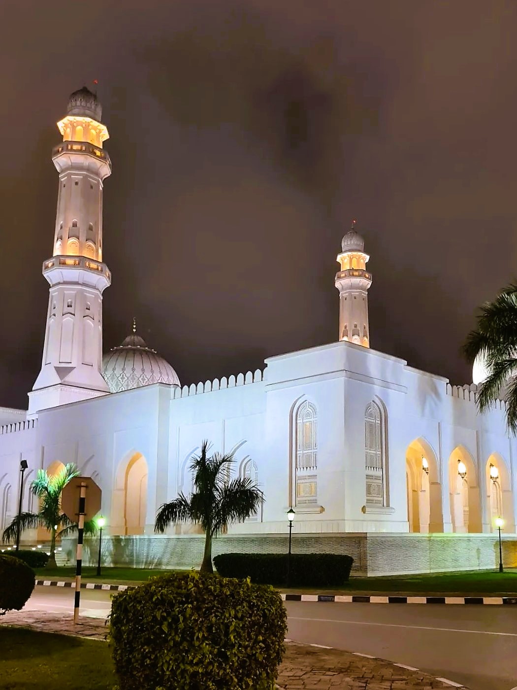 Noční pohled na bílou mešitu sultána Qaboose v Salalah  s dvěma minarety 