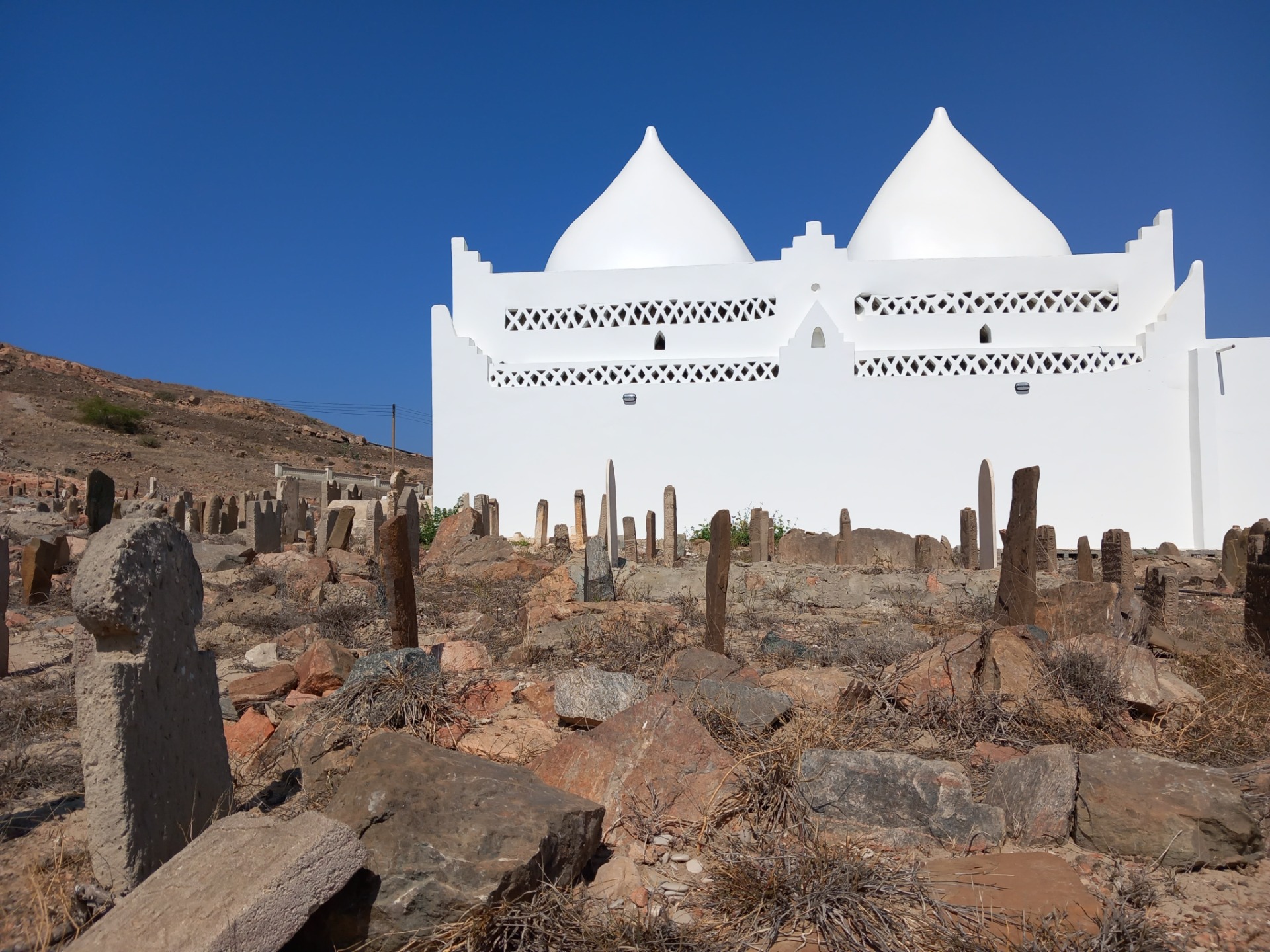 Hrobka Bin Aliho (Tomb of Bin Ali) se dvěma bílými kopulemi v malém přístavním městečku Mirbat v ománském regionu Dhofar.