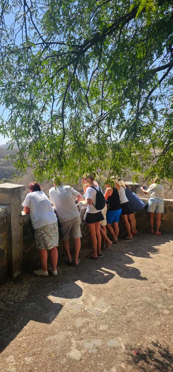 Skupina turistů stojí v řadě u vyhlídky v Tawi Atair v Ománu,