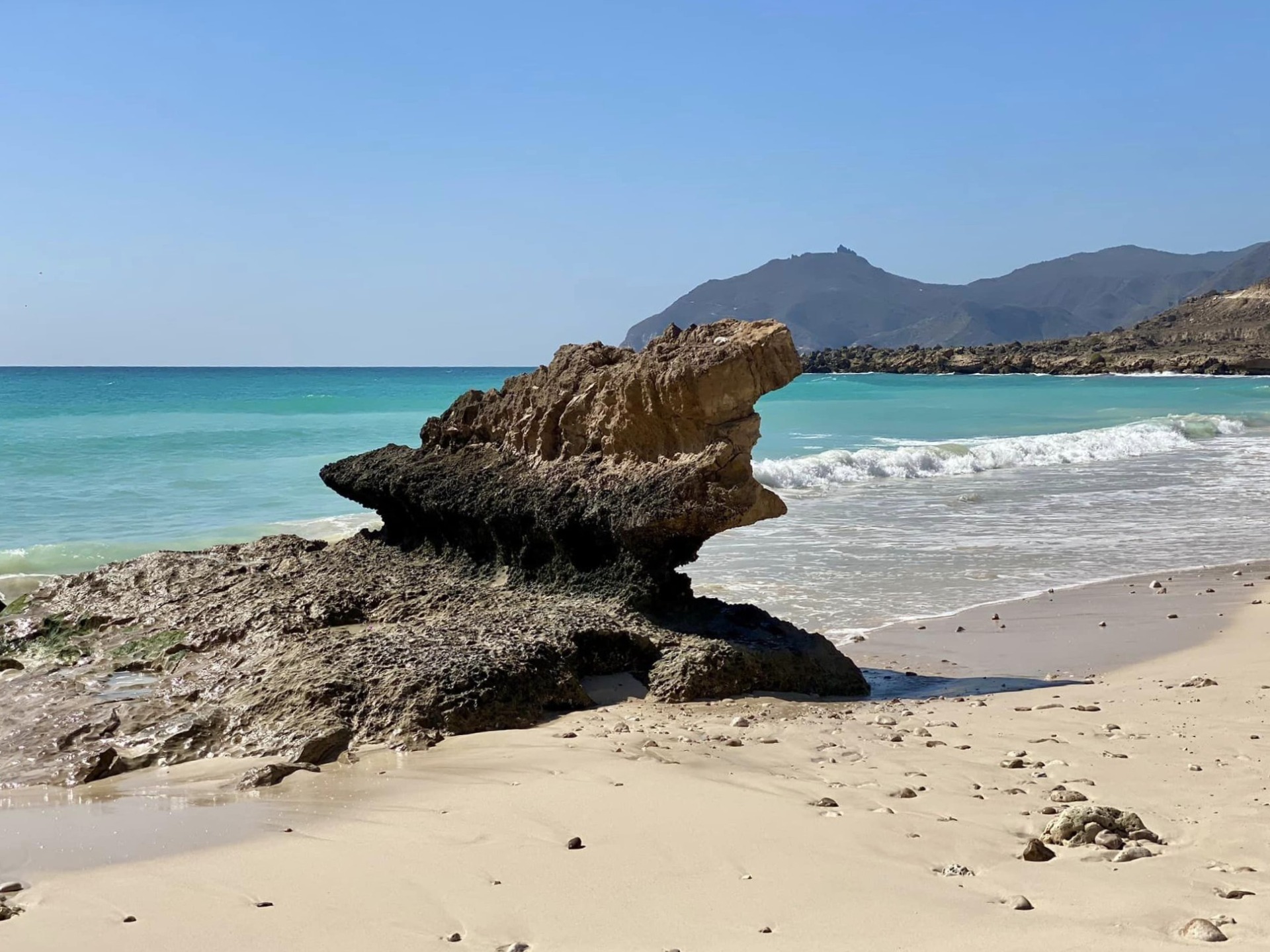 Skalní útvar u tyrkysové pláže na Fazayah beach v Ománu