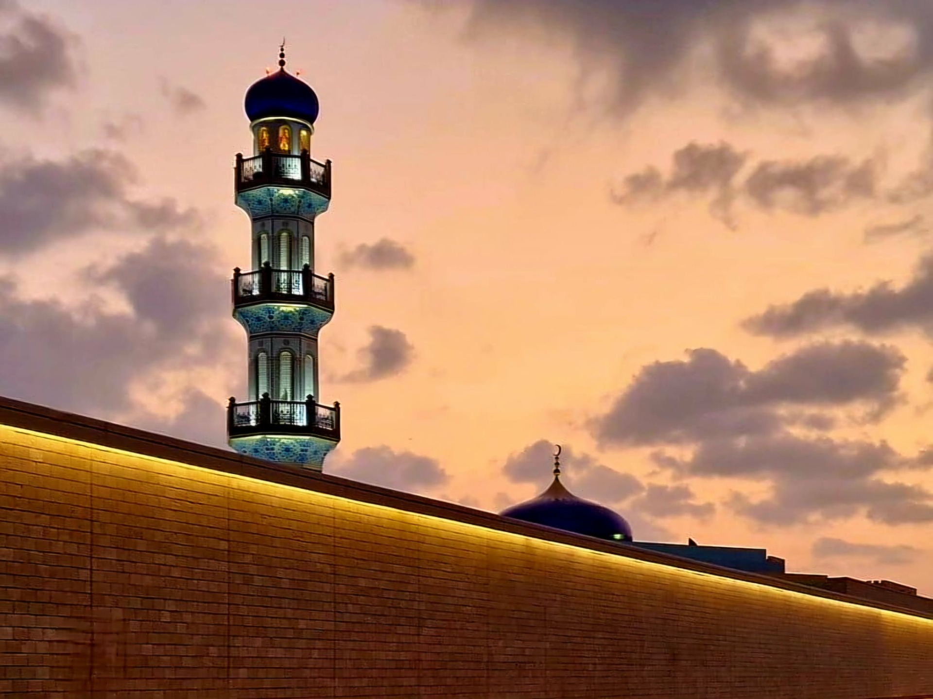osvětlený minaret mešity palácového areálu Al-Husn v Salalah, Omán při západu slunce
