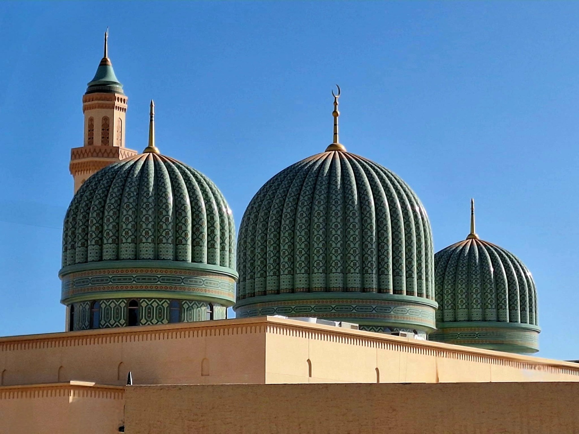 Zelené kupole mešity s mozaikovým vzorem a minaretem - mešita šejka Mustahaila v Taqah