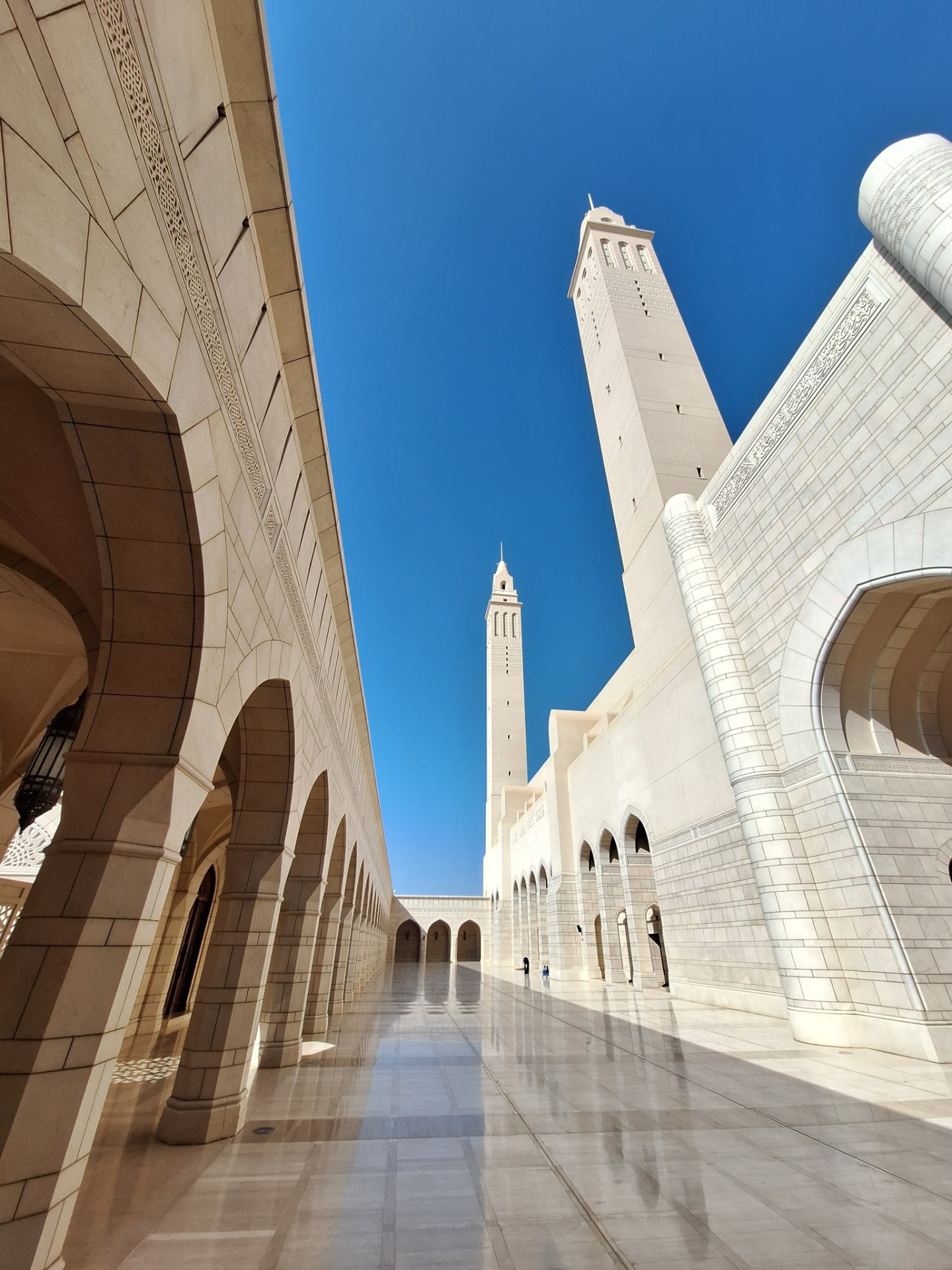 Bílá mešita sultána qaboose v Nizwa s vysokými minarety, oblouky a sloupy
