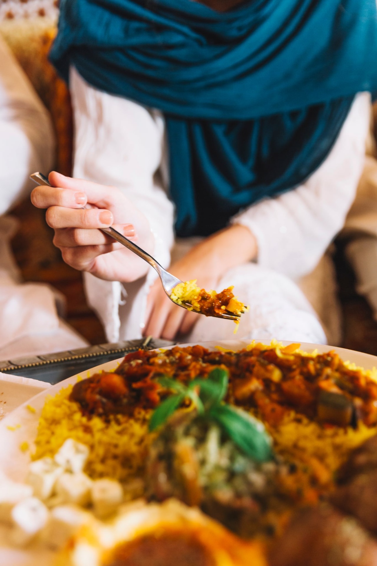 Žena drží v pravé ruce lžíci s tradičním ománským jídlem v restauraci jídlem